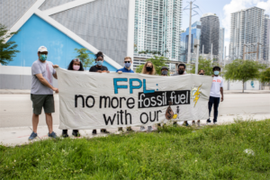 In August 2021, demonstrators from community groups gather outside FPL building in Miami where they have planted 250 flags to represent the 250,000 disconnections initiated by FPL after the moratorium on electricity shut-offs expired in the final months of 2020.
